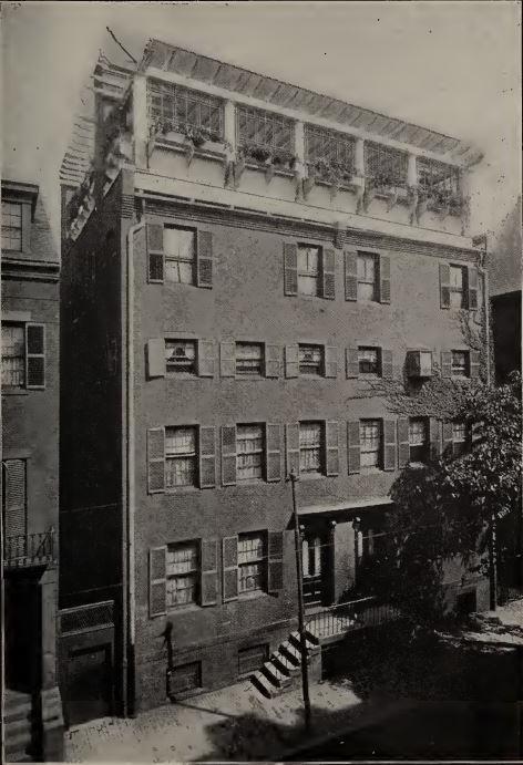 Black and white photo of a 5-story brick building. The photo is taken at an angle. A rooftop garden can be seen at the top of the building.